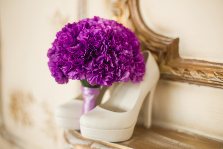 the violet bridal bouquet lies on a gold fireplace near white shoesの写真素材