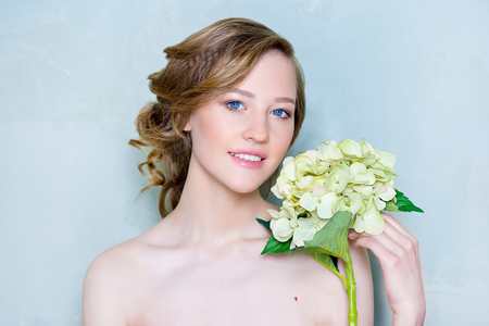Portrait end of beautiful model blue eyes and pink lips on a blue background with a flowerの写真素材