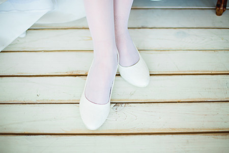 feet in white shoes and white stockings stand on a white timber floorの写真素材
