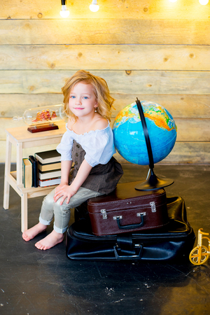 little girl posing traveler with world map, globe and booksの写真素材