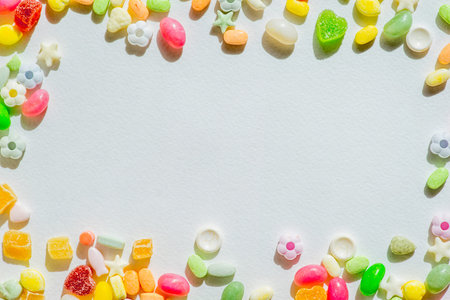 Frame of colorful chocolates of different shapes on a white sheet of paperの写真素材