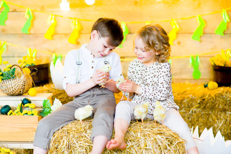 boy with the girl on the stage playing with chicken in easter decorationsの写真素材
