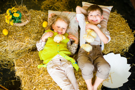 boy with the girl on the stage playing with chicken in easter decorationsの写真素材