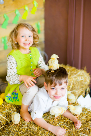 boy with the girl on the stage playing with chicken in easter decorationsの写真素材