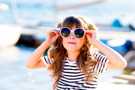 young girl sitting on the dock, laughing and smiling, looking aroundの写真素材