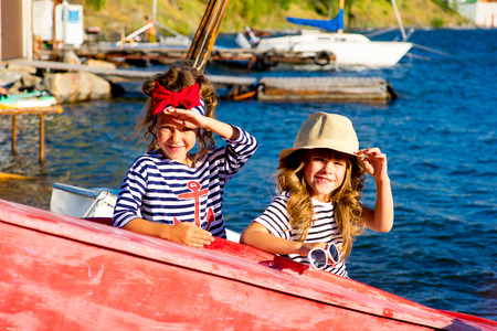 two young girls with the boat, looking around and smilingの写真素材