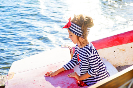 young girl with the boat, looking around and smilingの写真素材