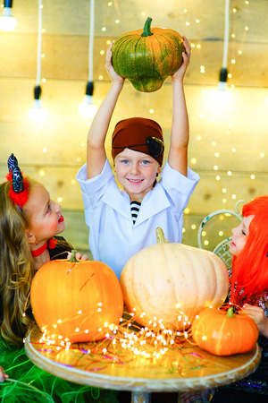 Happy group of pirate and demon children during Halloween party playing around the table with pumpkinsの写真素材