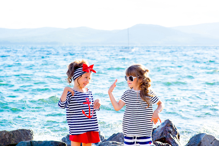 two young girls near the sea rock looking around and smilingの写真素材