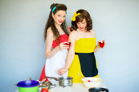 Two pinup housewifes in the kitchen trying to cook somethingの写真素材