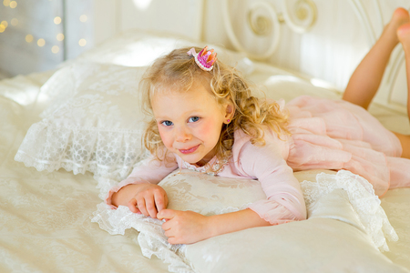 little princess on the bed in classic dress and vintage atmosphere of the roomの写真素材