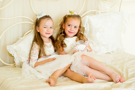 two little princess on the bed in classic dress and vintage atmosphere of the roomの写真素材