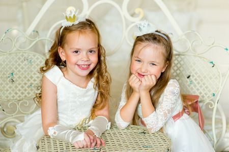 two little princess near the table in classic dress and vintage atmosphere of the roomの写真素材