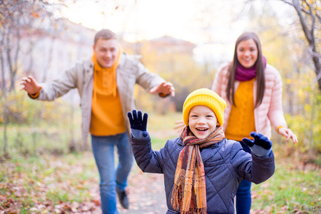 family playing catch-up on a footpath in autumn parkの写真素材