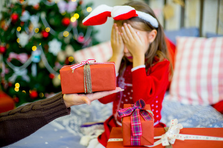 happy child girl with rabbit ears near a decorated Christmas tree surprized by Christmas giftsの写真素材