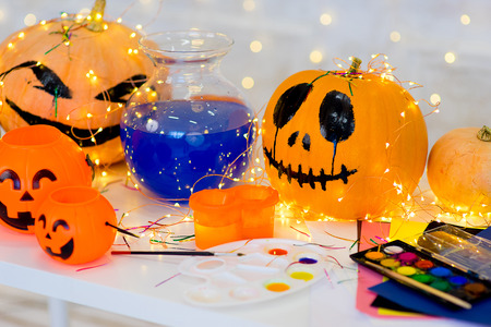 Table with Halloween pumpkins and bottle of blue potion, paintsの写真素材