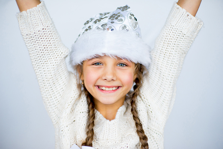 portrait of a girl with a Christmas present near Christmas tree in the white roomの写真素材