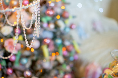 Christmas tree with gifts beside the bed, floor lamp, wrought iron chairs and table. Christmas interior in pastel colorsの写真素材