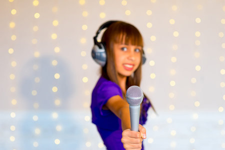 Girl with headphones singing on karaoke solo on background of lights