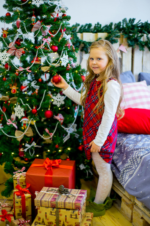 happy child girl with elf boots near a decorated Christmas tree surprized by Christmas giftsの写真素材