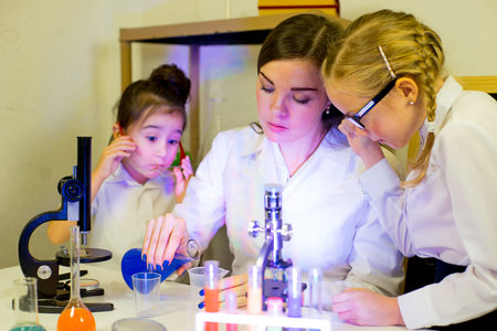 kids making science experiments with their teacher in laboratory. education