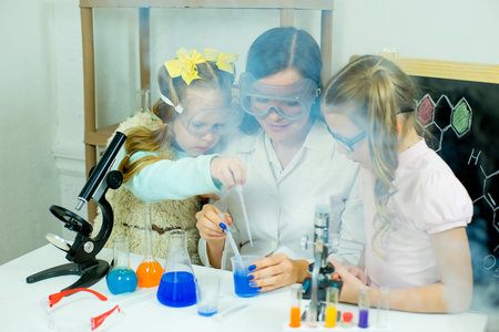 kids making science experiments with their teacher in laboratory. education