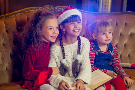 Santa Claus and group of girls sitting in Christmas room and reading a book. Christmas home decorの写真素材
