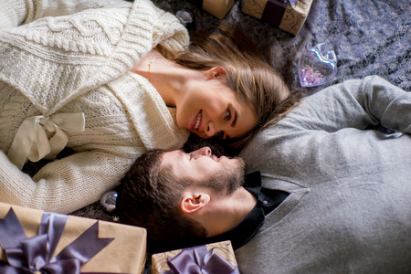 Happy couple of lovers lying on the bed between Christmas gifts. Christmas interior. Lovers togetherの写真素材