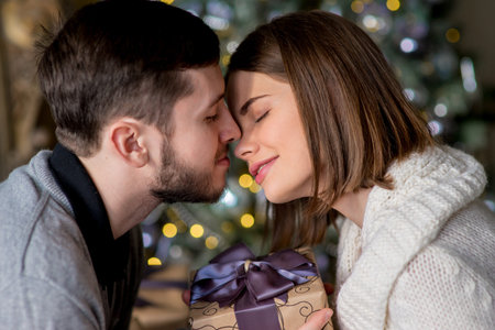 Happy couple of lovers sitting on the bed. Christmas interior. Lovers together