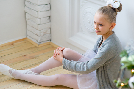 Young ballet dancer sitting near Christmas tree on the wooden floorの写真素材