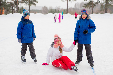 two boys helps girl learn to skateの写真素材