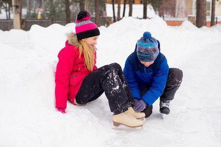 young boy helps to the girl ties bootlaces up skatesの写真素材