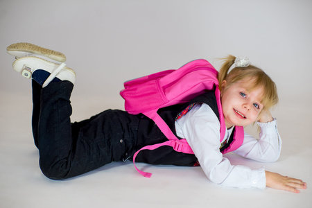 portrait of young lying schoolgirl with schoolbag