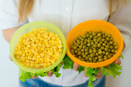 girl holding canned peas and corn closeupの写真素材