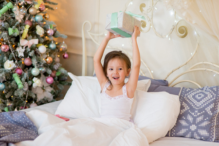 Child girl wake up in her bed in Christmas morningの写真素材