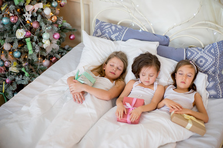 Child girls sleep in their bed in Christmas morningの写真素材