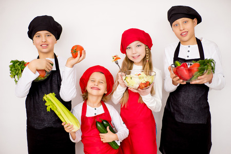 four young chefs going to prepare a salad isolatedの写真素材