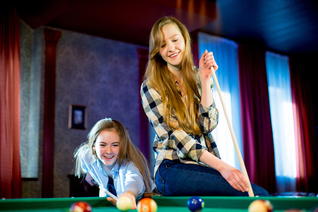 two girls playing billiardの写真素材