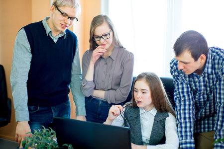 four employees looking at laptop