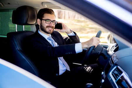 Businessman talking on a cell phone in a carの写真素材