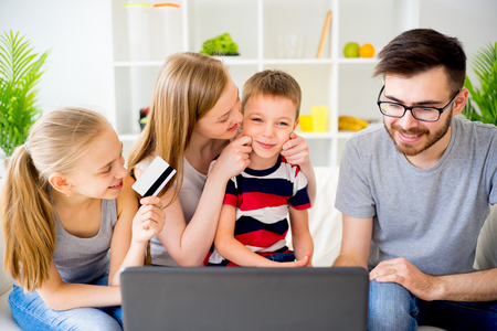 Happy family of four shopping online with a laptopの写真素材