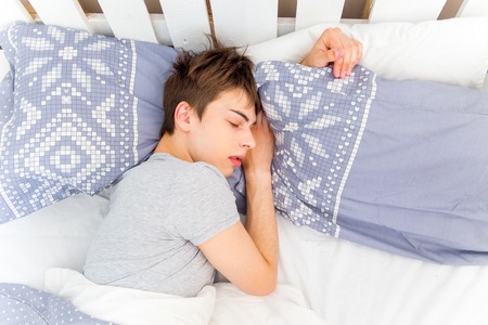 Handsome young man sleeping in white beddingの写真素材