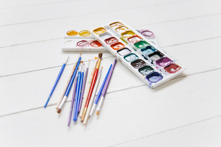 Set of watercolor paints and paintbrushes on a tableの写真素材