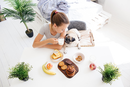 Young woman with her dog in a bed. Breakfast in bedの写真素材