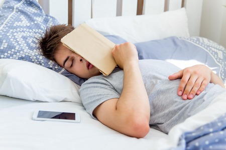 A young man waking up in bed in the morningの写真素材