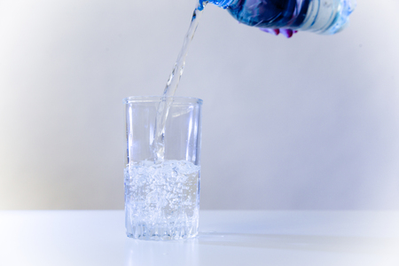 Glass of pure water on a white wooden kitchen tableの写真素材