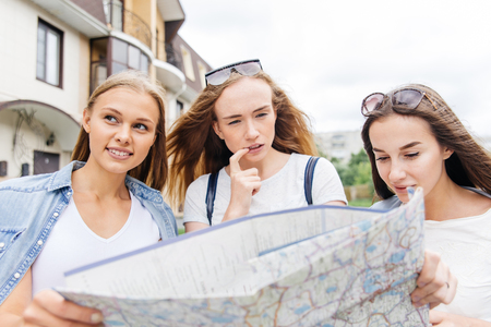 Beautiful woman traveler holding location map in hands in a cityの写真素材