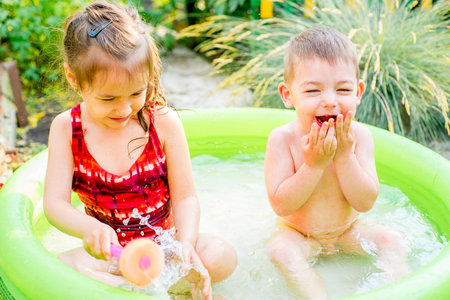 Children playing in inflatable baby pool. Kids swim and splash