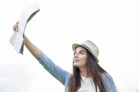 Beautiful woman traveler holding location map in hands in a city