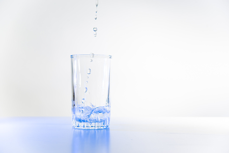 Glass of pure water on a white kitchen tableの写真素材